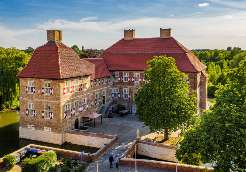 Schloss Oberwerries umgeben von vielen grünen Bäumen und blauen Himmel